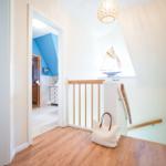 Flur mit Holzboden, Treppe und Blick in Sauna und Schlafzimmer.