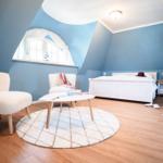 Schlafzimmer mit blauen Wänden, weißem Bett und Rundfenster.