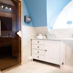Badezimmer mit Dusche, Waschbecken und Holzsauna