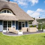 Haus mit Strohdach und Terrasse mit Liegen und Sitzgruppe.