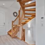 Holztreppenhaus mit Eingangstür und Wandbild.