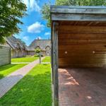 Holzüberdachter Bereich mit Blick auf traditionelle Dachhäuser und grünen Rasen.