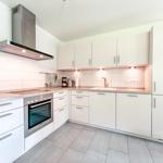 Moderne Küche mit weißen Schränken, Edelstahlgeräten und Holzoberflächen.