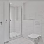 Badezimmer mit Dusche, Toilette und Toilettenpapierhalter.