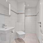 Badezimmer mit Waschbecken, Spiegel und Toilette.