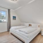 Schlafzimmer mit Doppelbett, Fenster und Nachttisch