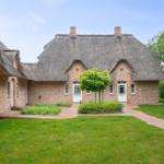 Rotes Backsteinhaus mit Strohdach und gepflegtem Garten