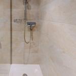 Dusche mit Handbrause und bodengleicher Badewanne.