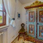 Ein Raum mit einem bemalten Schrank, einem Stuhl und einem Fenster mit Blick auf die Außenterrasse.