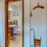 Badezimmer mit Waschbecken und Toilette. Holzrahmen und bemalter Eimer.