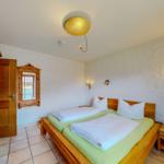 Schlafzimmer mit Holzbett, Nachttisch und dekorativen Wandlampen.