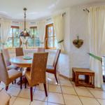 Esszimmer mit runden Tisch, Stühlen und Fenstern mit weißen Vorhängen.