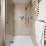 Duschkabine mit Duschbrause, Handtuchhalter und Heizkörper.