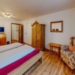 Schlafzimmer mit Bett, Kleiderschrank und Sessel.