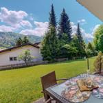 Terrasse mit Tisch und Stühlen, Blick auf grünen Garten und Berge.