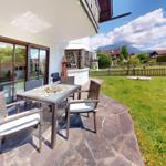 Terrasse mit Sitzgruppe, Garten und Bergblick.