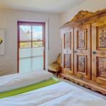 Schlafzimmer mit Bett, Holzschrank und Fensterblick.