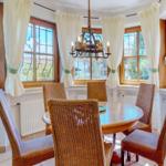 Runder Esstisch mit sechs Stühlen in einem Raum mit Fenstern und Vorhängen.