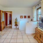 Wohnraum mit Badewanne, TV und Holzmöbel. Türöffnungen führen in andere Räume.