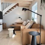 Wohnzimmer mit Sofa, Stehlampe und TV an der Wand.