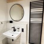 Badezimmer mit Waschbecken, Spiegel und Heizkörper