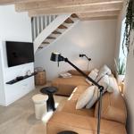 Wohnzimmer mit Sofa, Fernseher und Treppe