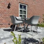 Terrasse mit grauem Tisch und Stühlen vor rotem Backsteinhaus