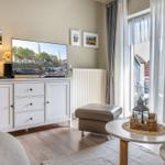 Wohnzimmer mit TV, Couch und Blick auf Balkon