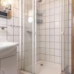 Badezimmer mit Dusche, Waschbecken und Spiegel.