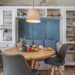 Rundes Holztablett mit Stühlen und Küchenschränken im Hintergrund.