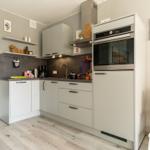 Küche mit grauen Schränken, Edelstahl-Küchenzeile und Holzboden.