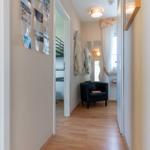 Flur mit Holzboden, schwarzer Sitzgelegenheit und Spiegel an der Wand.