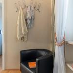 Schwarzer Sessel neben Fenster mit Bücherregal und Haken an Wand.