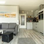 Wohnbereich mit Sofa, Couchtisch und Küche in moderner Einrichtung.