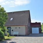 Ein Haus mit Garage, weiße Bank und grüner Umgebung.