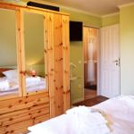 Schlafzimmer mit Holzschrank, Bett und Fernseher an der Wand.