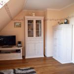 Schlafzimmer mit TV, Schrank und Garderobe. Holzboden und Dachschräge.