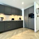 Moderne Küche mit grauen Schränken und Marmorarbeitsplatte.