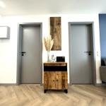 Eingangsbereich mit Holzschrank, zwei Türen und blauer Wand im Hintergrund.
