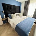 Schlafzimmer mit Bett, blauer Wand und Vorhängen.