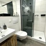 Badezimmer mit Dusche, Toilette und Waschbecken mit Spiegel.