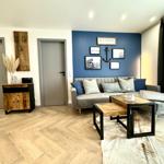 Wohnzimmer mit Sofa, Couchtisch und blauer Wand mit Bildern.