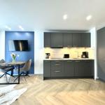 Moderne Küche mit Essbereich und Fernseher an blauer Wand.