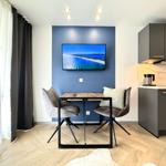 Küche mit Esstisch und Fernseher an blauer Wand.