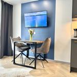 Essbereich mit Tisch, zwei Stühlen und Fernseher an blauer Wand.