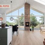 Großes Wohn- und Esszimmer mit Holzboden, großen Fenstern und Kamin.