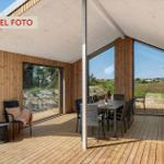 Terrasse mit Essbereich und Sitzgelegenheit, Holzwand und große Fenster