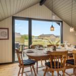 Esszimmer mit Holztisch, Stühlen und Blick auf die Landschaft.