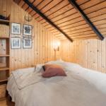 Schlafzimmer mit Holzwand, Bett und Regal. Decke mit Holz und schwarzen Balken.