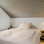 Schlafzimmer mit Dachschräge, Bett, Nachttisch und Lampe.